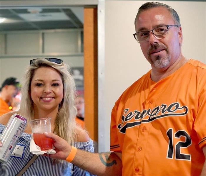 woman in blue shirt toasts man in orange baseball jersey