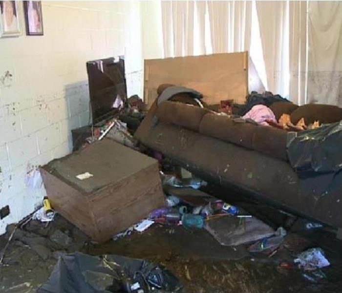 Living room with turned over couch and foot stool in a flooded apartment