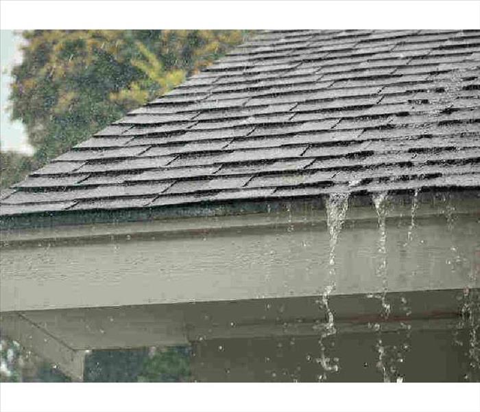 Roof with water streaming down the shingles after a rainstorm