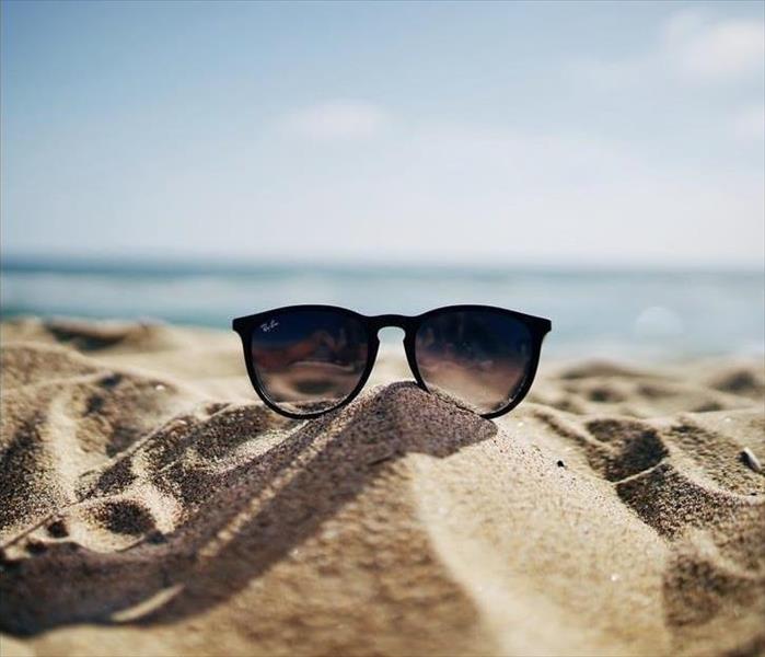 Ray-Ban sunglasses on sand pile in front of ocean