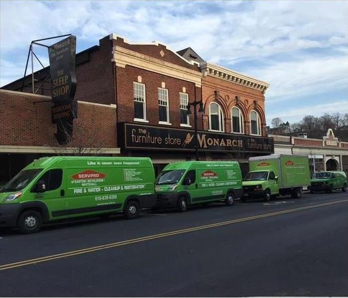 Three green SERVPRO vans parked in front of a furniture store