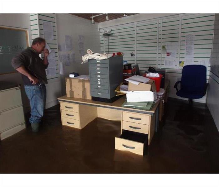 Man standing in a flooded office with over a foot of water